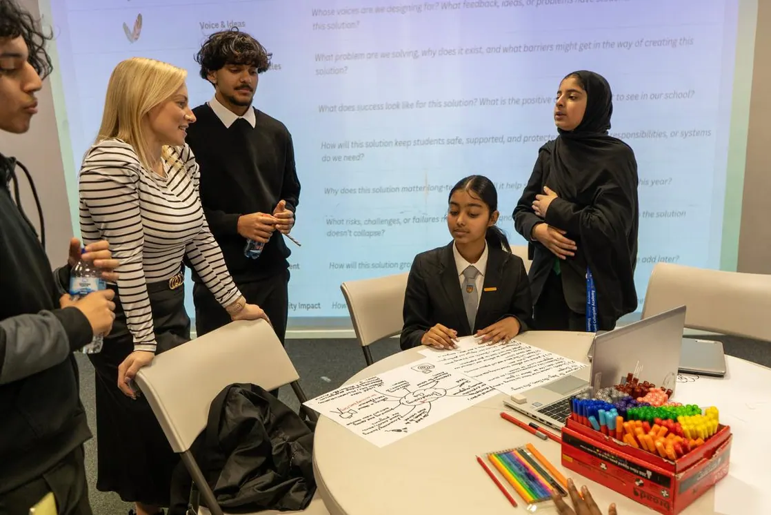 Students designing a project for their school, with a mind map on the table and design questions on the screen