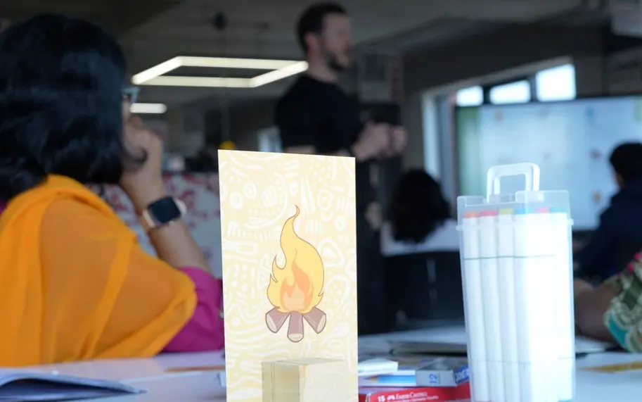 A Campfire icon card on a workshop table while a facilitator talks to the room