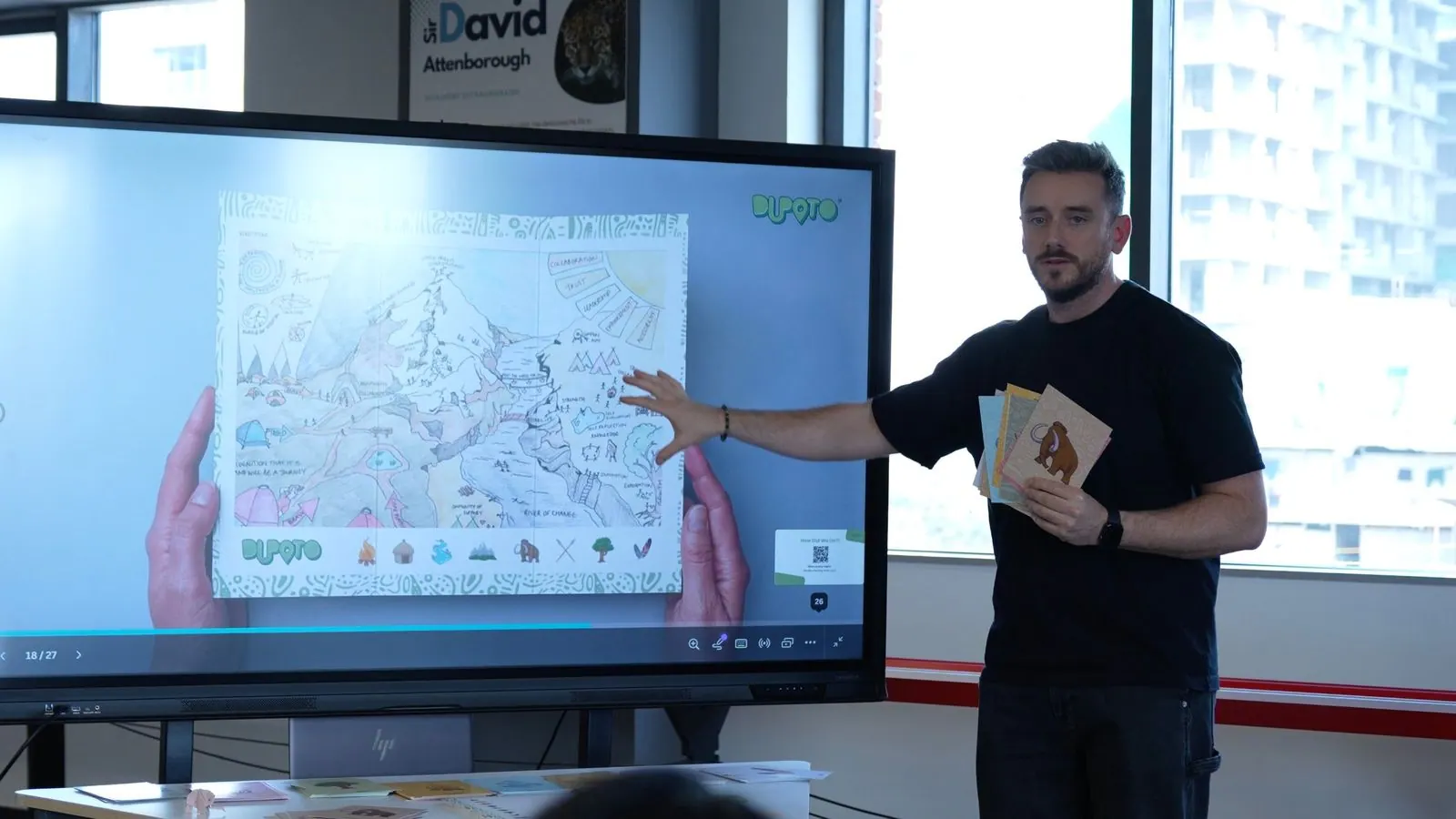 Elfyn Wyn Jones talking a group through a Territory Map on screen, holding a set of icon cards