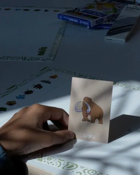 A student's hand holding up the Mammoth card in a pool of sunlight