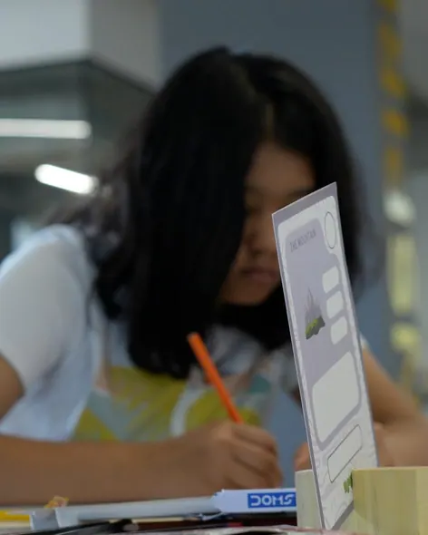 A student drawing her map behind a Mountain prompt card